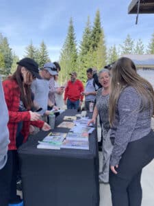 People stand around a table of publications, outdoors
