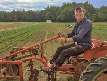 A woman sits on a red tractor.