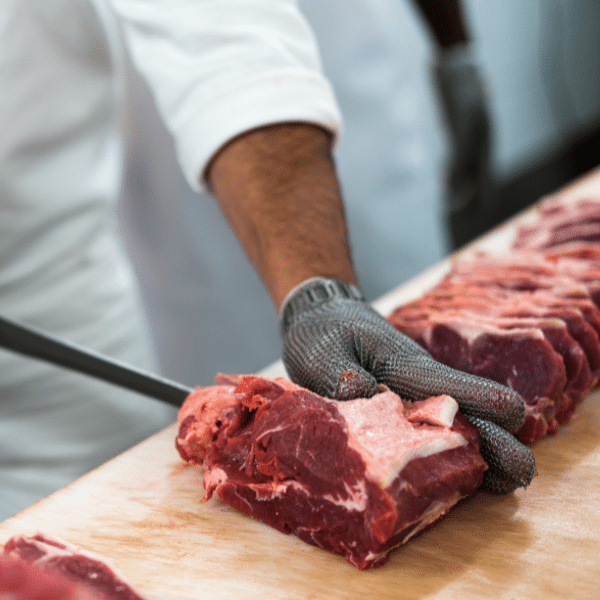 gloved hand holding meat in process of being sliced