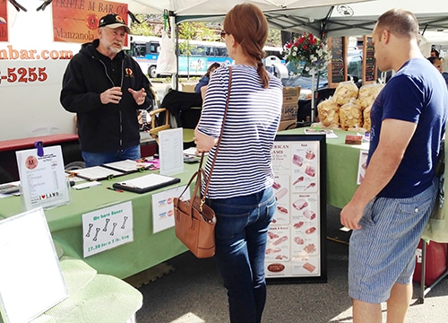 A man selling meat at a farmers market.