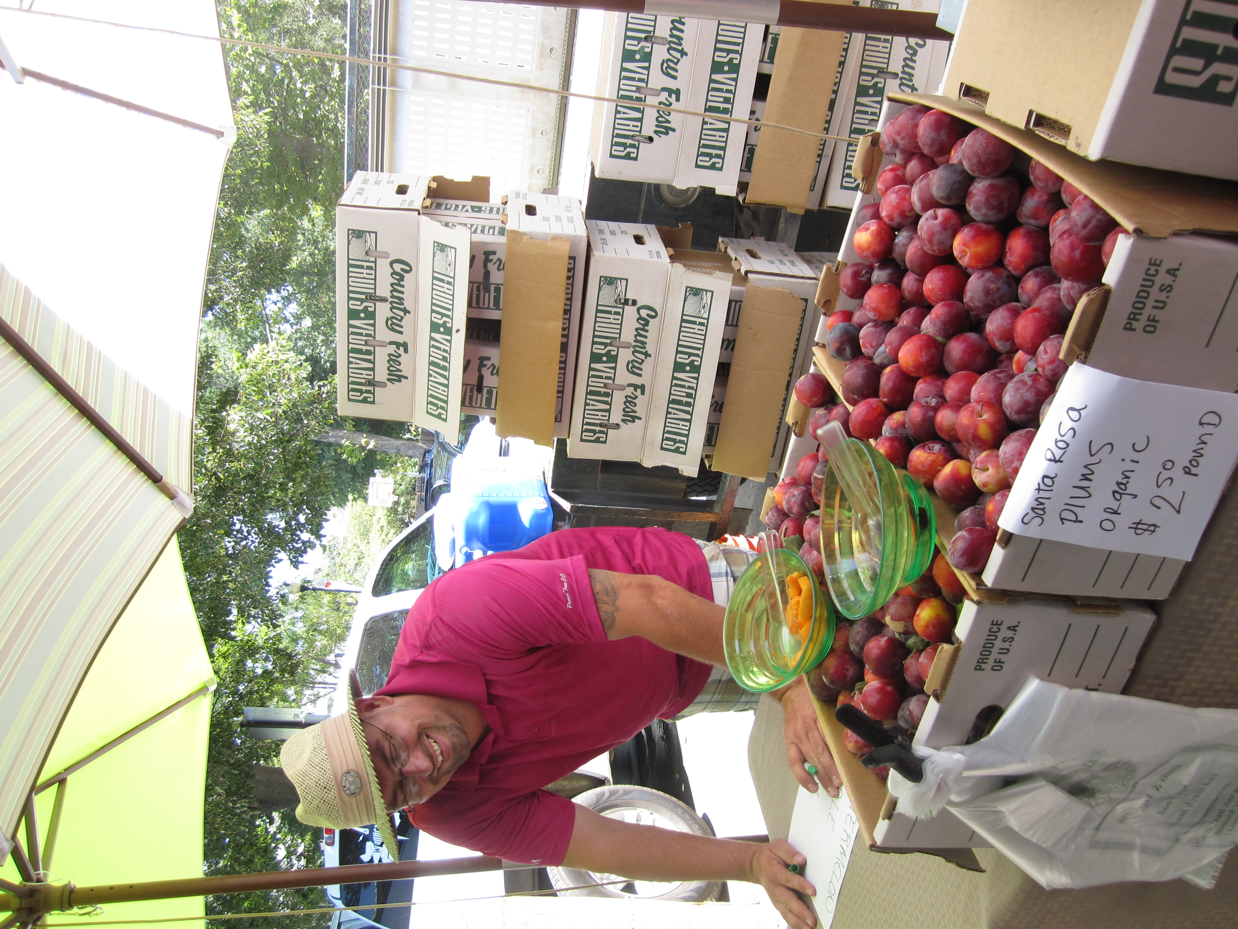 Man marketing plums at farmers market