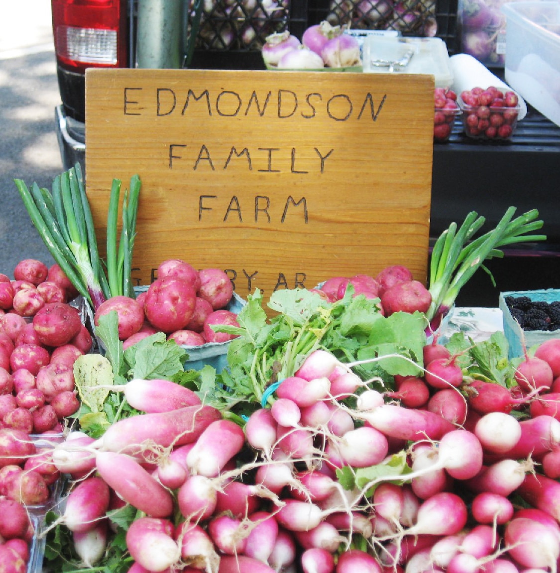Cartel hecho a mano en un mercado de agricultores con un montón de tubérculos