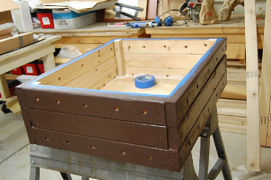 A wooden worm bin is being built