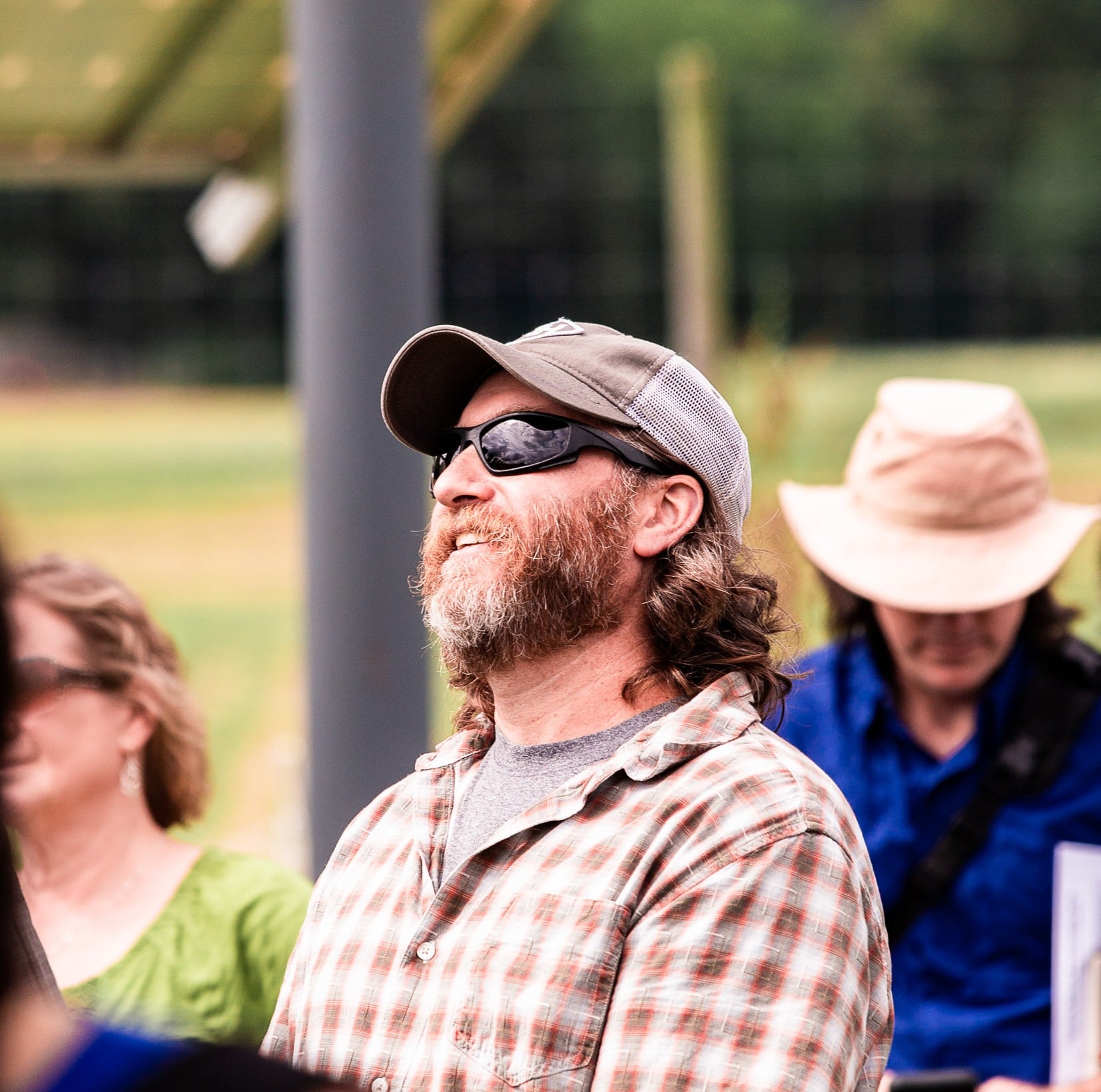 bearded man in sunglasses and hat, looking upward