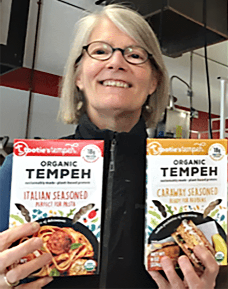 Sarah Spear holding boxes of her product, Tooties Tempeh