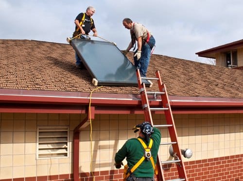 Crew Installing a flat plate solar water heating collector.