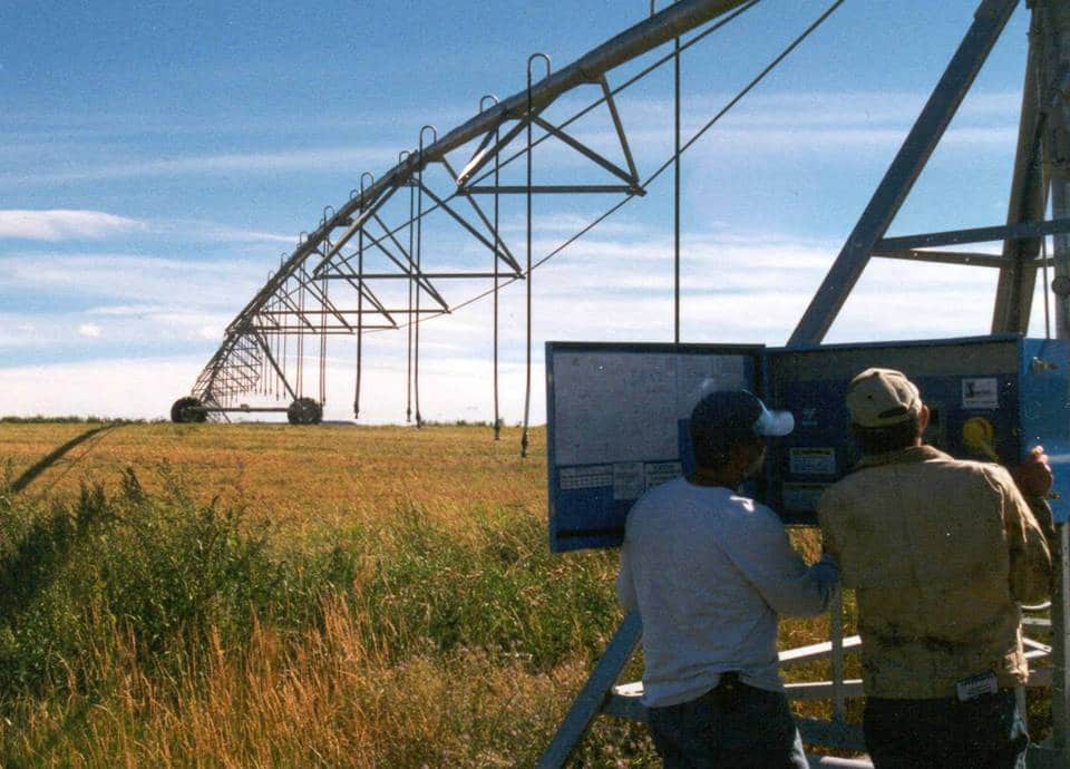 men working checking a control box of a pump in the field