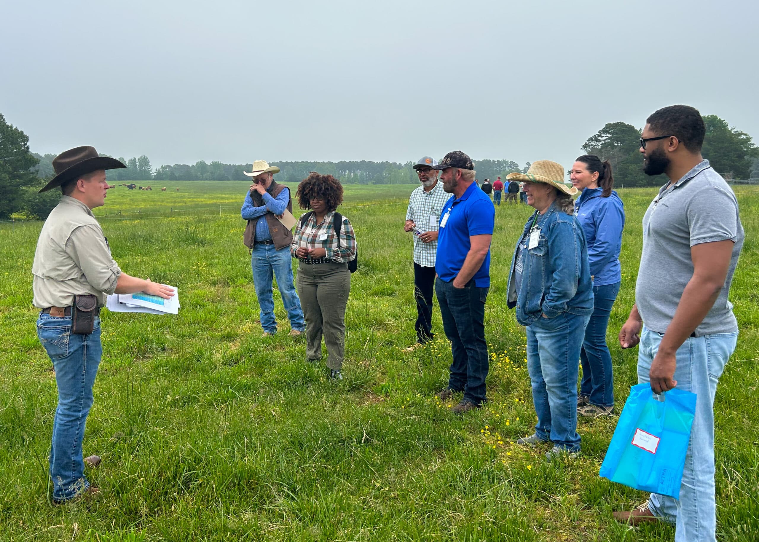 Un grupo está de pie en un campo mientras un instructor habla.