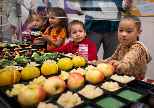 BTFS kids in cafeteria line Children standing in a cafeteria line with apples, broccoli, and other fruit and vegetables