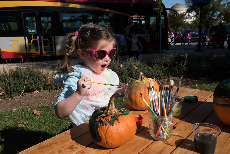 a child paints on a pumpkin