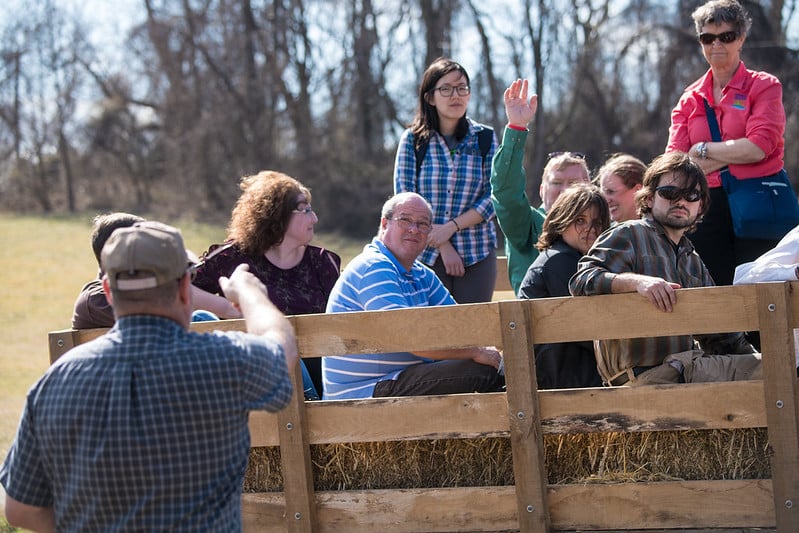 a group of people outdoors riding on a wagon