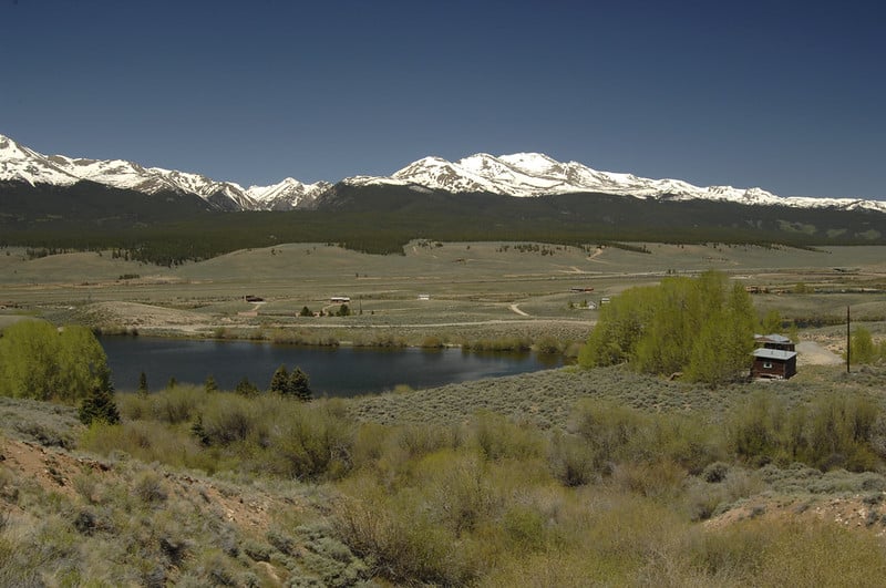 range landscape with snowy mountains in background, under blue sky