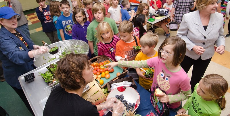 A line of children in front of a table with fresh produce in bowls
