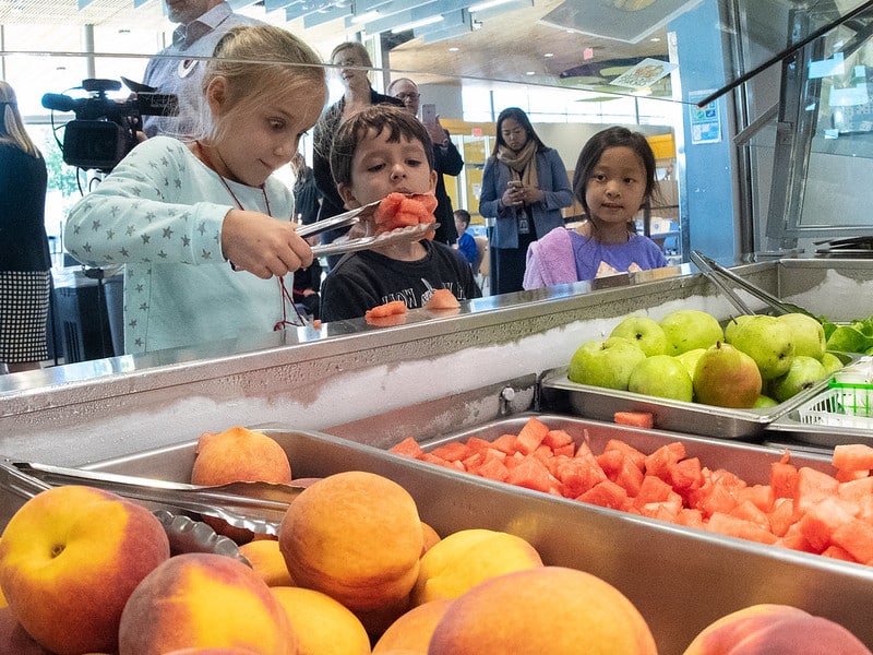 children serving themselves fruit from trays