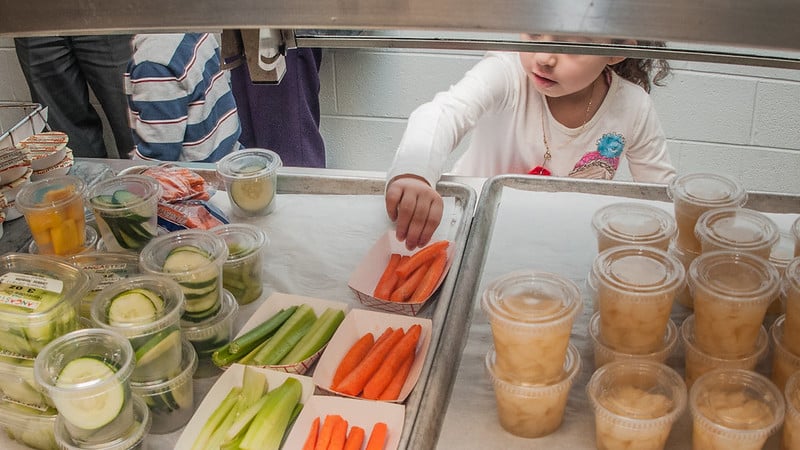 Child in cafeteria line reaches for carrots